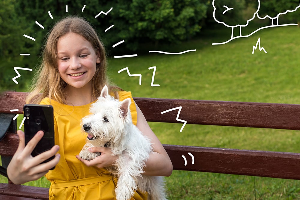 West Highland Terrier and a girl take a selfie snap on a park bench